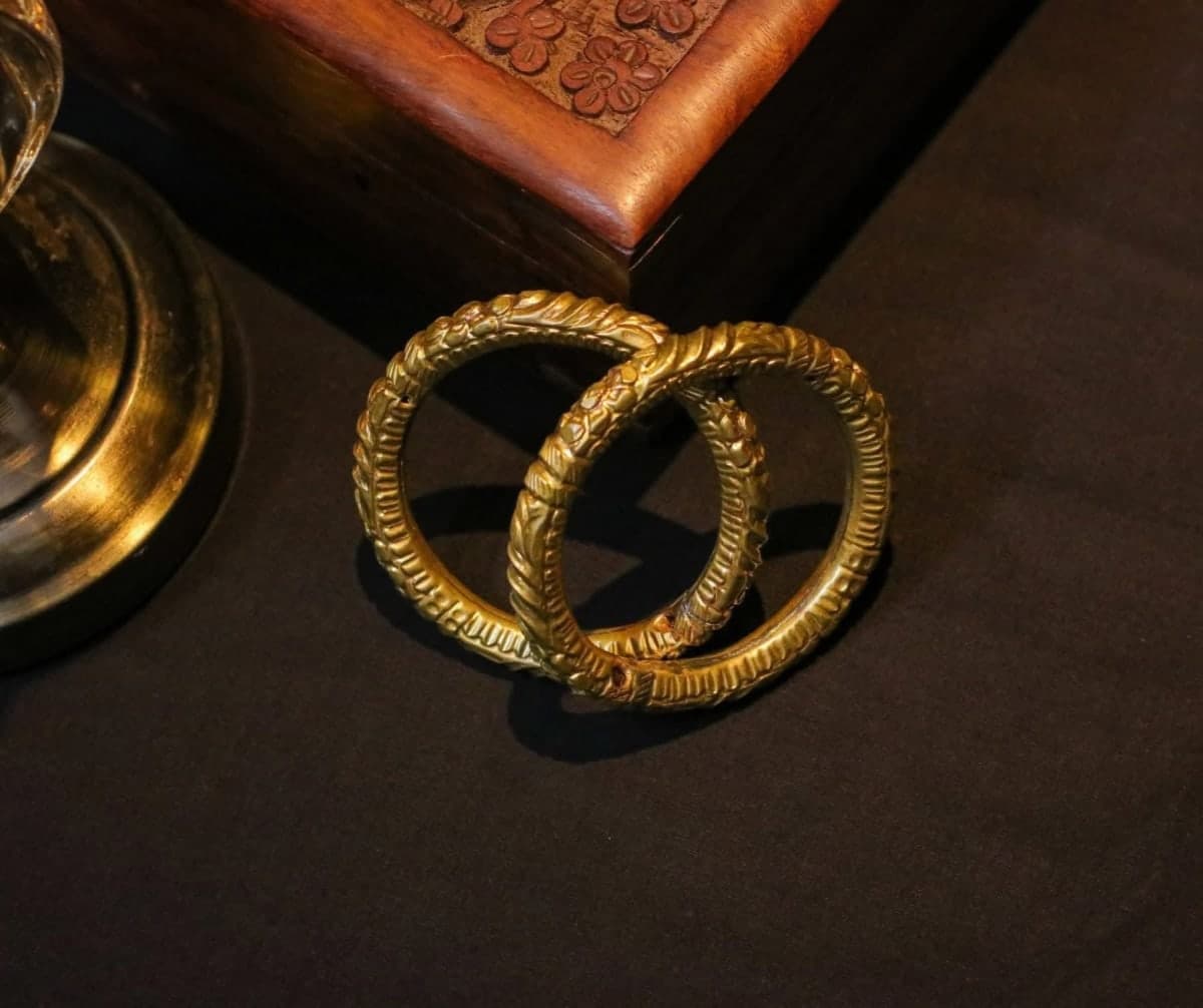 Pair of silver-toned Golap Bala bangles with full intricate traditional designs on a light brown background.